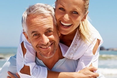 Couple with golden tans embracing and smiling outdoors