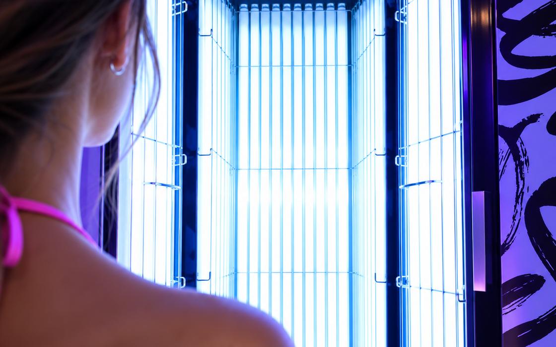 Woman stepping into a Zoom Tan stand-up UV tanning booth